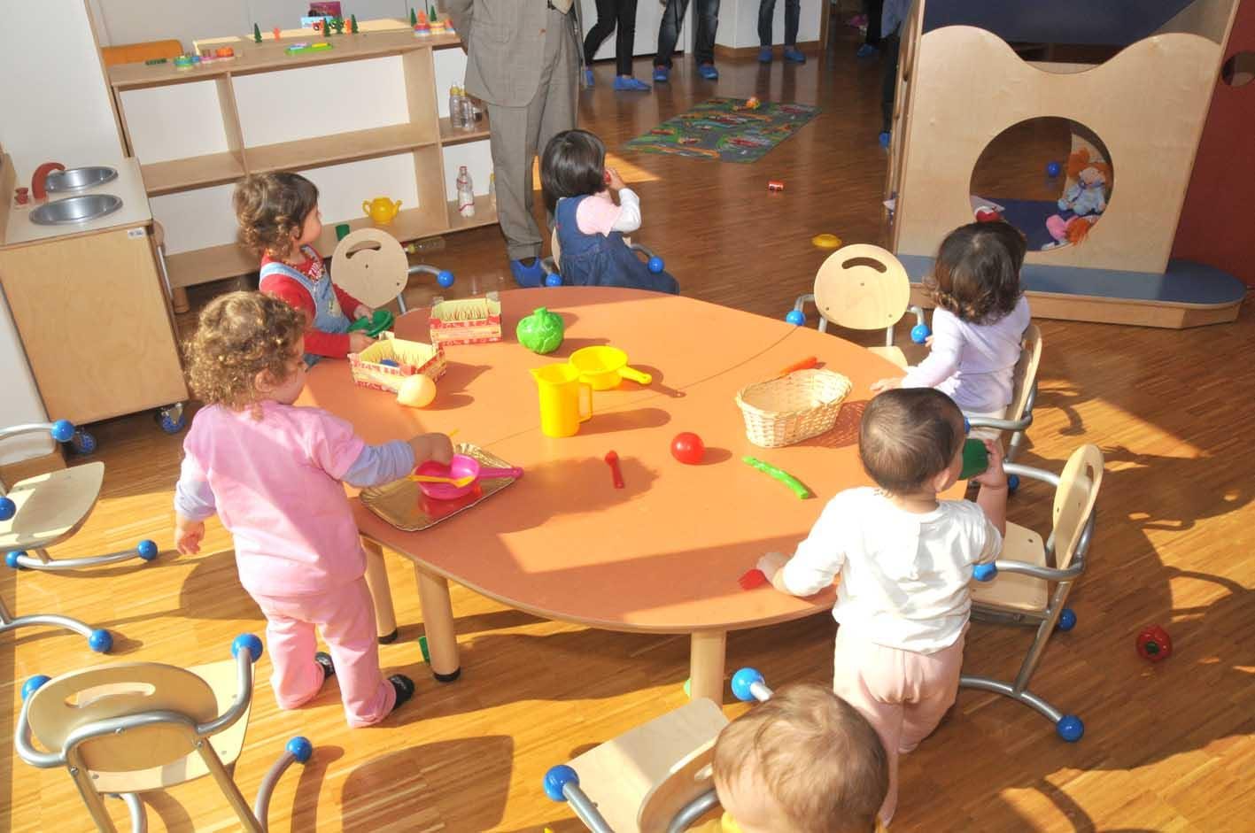 bambini che giocano in un tavolo roondo con vari giochi in un asilo nido