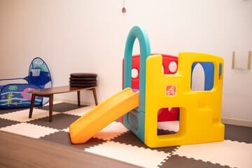 stanza di asilo nido con scivolo scrivania e un tappeto a scacchi bianco e nero